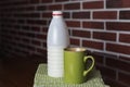 Natural bio milk product. Half bottle of natural milk, kefir and green mug, on a beautiful light green color napkin, wooden table