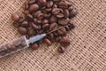 Brown roasted coffee beans in syringe on burlap