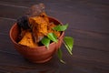 Natural Chaga mushroom pieces in a bowl with birch twig on a dark wooden background