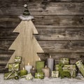 Natural christmas decoration in green and brown on wooden background with presents and candles. Royalty Free Stock Photo