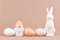 Natural colored Easter eggs with simple stripes and dots pattern with bunny shaped egg cup and sculpture beige background Royalty Free Stock Photo