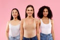 Natural concept. Portrait of three diverse models women smiling to camera posing on pink background, studio shot Royalty Free Stock Photo
