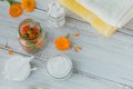 Natural cosmetic cream, balm or ointment, cotton pad, sticks and towels with calendula flowers on light background