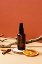 Natural cosmetic package. Amber glass spray bottle with dried orange slice, cinnamon sticks, wooden branch Royalty Free Stock Photo