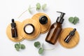Natural cosmetics concept. Top view photo of glass bottles and cream jar on wooden stands and eucalyptus leaves on isolated white Royalty Free Stock Photo