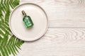 Natural cosmetics perfume essential oil serum in green glass bottle with dropper on plate, wooden background with green