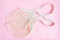 Natural cotton mesh bag on a pink background. Zero waste concept with copy space for text. Simple layout, top view