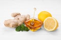 Natural cough remedies. Bowl with honey, ginger, mint and lemon on white table Royalty Free Stock Photo