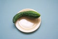 Natural cucumber of an unusual shape on a yellow plate on a blue background.