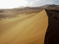 Natural curved ridge line and footprint on rusty red sand dune with strong sunlight on desert landscape with a traveler standing Royalty Free Stock Photo