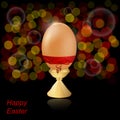 Natural easter egg on a stand with a red bow on a dark background.