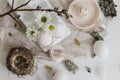 Natural easter eggs, feathers, willow branches, nest and candle on rustic white table flat lay. Stylish rural Easter still life in