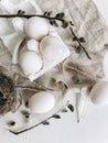 Natural easter eggs, feathers, pussy willow branches on rustic cloth on white aged table. Flat lay