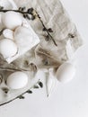 Natural easter eggs, feathers, pussy willow branches on rustic cloth on white aged table. Flat lay