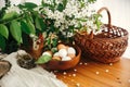 Natural Easter eggs, wicker basket, bird nest and cherry flowers on rustic table. Happy Easter, atmospheric moment. Rural still