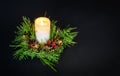 Natural eco-friendly Christmas wreath with a burning candle in the middle on a black background. Space for text