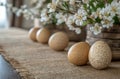 Natural eggs arranged on a burlap cloth with delicate white flowers in a sunlit setting, creating a rustic and Royalty Free Stock Photo