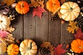 Natural fall frame of pumpkins and leaves on a rustic dark wood background