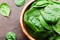 Natural fresh baby spinach leaves in wooden bowl on vintage stone table. Organic healthy food.