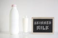 Natural fresh skimmed milk in a glass next to a bottle against a white background. Empty copy space Royalty Free Stock Photo