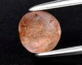 Natural gemstone orange Padparadscha sapphire on gray background