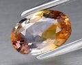 Natural gemstone orange Padparadscha sapphire on gray background