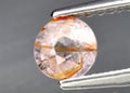 Natural gemstone orange Padparadscha sapphire on gray background