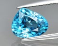 Natural gemstone blue zircon in tongs on a gray background Royalty Free Stock Photo