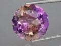 Natural gemstone colored ametrine in thongs on a gray background. Natural Bolivian bicolor yellow purple ametrine