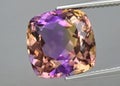 Natural gemstone colored ametrine in thongs on a gray background. Natural Bolivian bicolor yellow purple ametrine