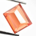 Natural gemstone orange Padparadscha sapphire on gray background