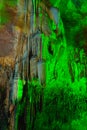natural gray stalagmite or stalactite in dark cave with abstract green led light
