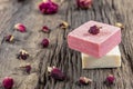 Natural hand made soap with dry pink roses on vintage wooden board. Spa