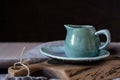 Natural handcrafted dishware. Wooden brown cutting board and ceramic blue cream jug with gray linen napkin.