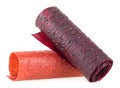 Natural and healthy snack food - multicolored tubes of fruit pastille from apples, raspberry and currant on white background.