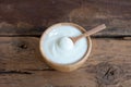 Natural homemade plain organic yogurt in wooden bowl and wood spoon on wood texture background Royalty Free Stock Photo