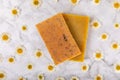 Natural homemade soap with chamomile flowers on a wooden table.