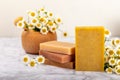 Natural homemade soap with chamomile flowers on a wooden table.