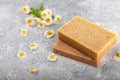 Natural homemade soap with chamomile flowers on a wooden table.