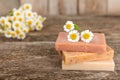 Natural homemade soap with chamomile flowers on a wooden table.