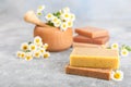 Natural homemade soap with chamomile flowers on a wooden table.