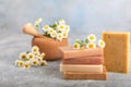 Natural homemade soap with chamomile flowers on a wooden table.