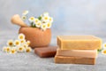 Natural homemade soap with chamomile flowers on a wooden table.