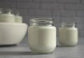 Natural homemade yogurt in a glass jar with a yogurt maker on a gray background
