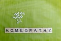 Natural Homeopathic Concept - Scattered Homeopathic medicine pills on banana leaf with Homeopathy text