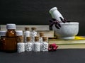 Natural Homeopathy Concept Ã¢â¬â Healing herbs in a mortar and pestle next to homeopathic medicine consisting a bottle of pills-