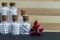 Natural Homeopathy Concept - Vintage homeopathic medicine bottles of pills with pink flower bud on wood and dark background