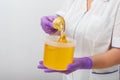 Natural honey sugar paste shugaring closeup. Women beautician holds jar wax of paste for sugar depilation shugaring