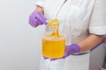 Natural honey sugar paste shugaring closeup. Women beautician holds jar wax of paste for sugar depilation shugaring