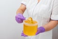 Natural honey sugar paste shugaring closeup. Women beautician holds jar wax of paste for sugar depilation shugaring